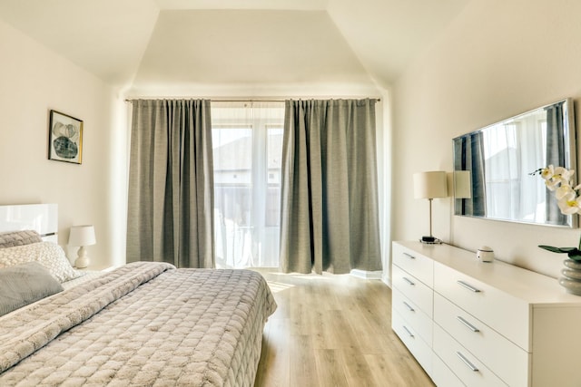 bedroom with lofted ceiling and light wood-type flooring