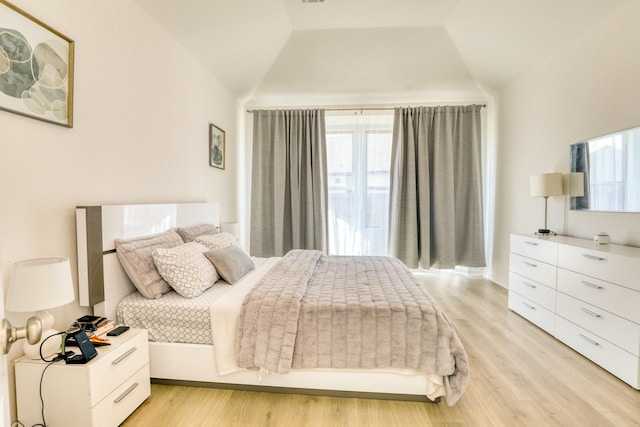 bedroom with vaulted ceiling, multiple windows, and light wood-style flooring