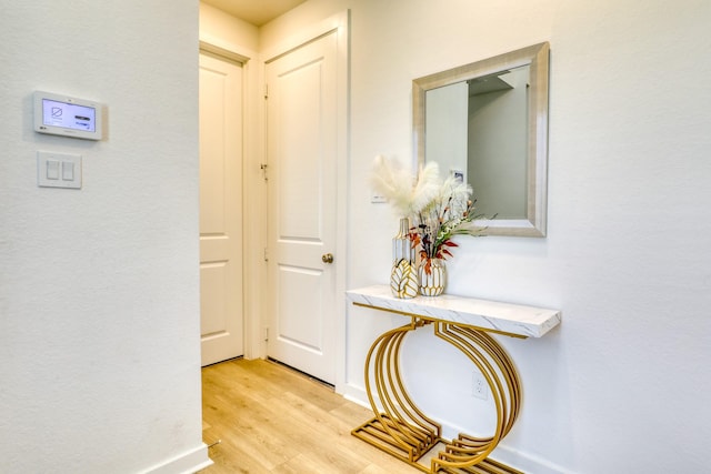 hallway featuring light wood-style flooring and baseboards