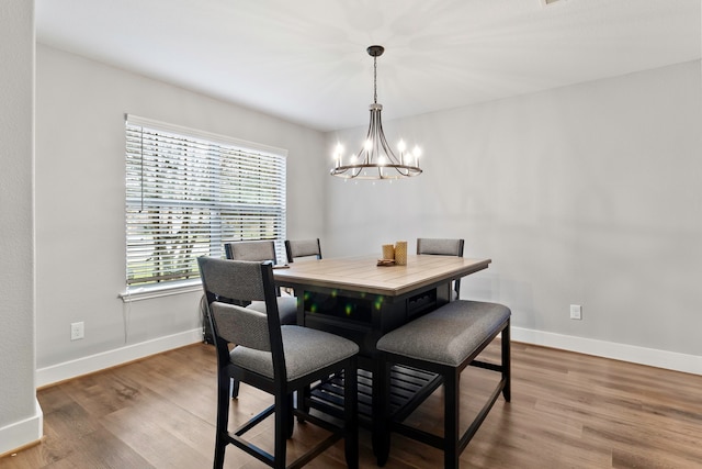 dining area featuring a notable chandelier, wood finished floors, and baseboards