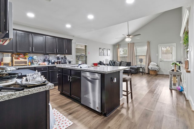 kitchen featuring lofted ceiling, a breakfast bar area, light wood-style flooring, stainless steel dishwasher, and a center island