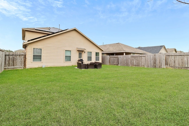 rear view of property with a fenced backyard, roof mounted solar panels, and a yard