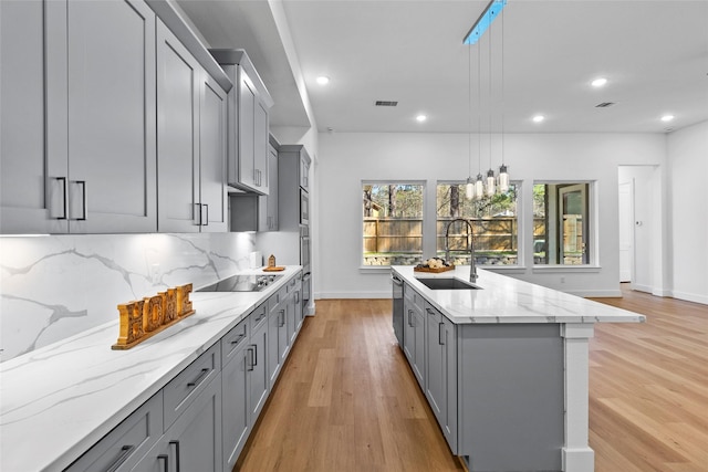 kitchen with tasteful backsplash, appliances with stainless steel finishes, gray cabinets, and a sink