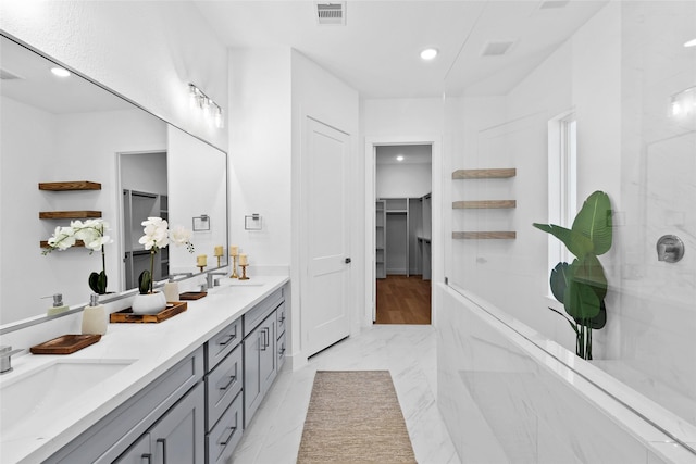 full bath featuring a walk in closet, double vanity, visible vents, a sink, and a walk in shower