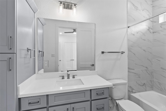 bathroom with ceiling fan, a textured wall, toilet, vanity, and shower / washtub combination