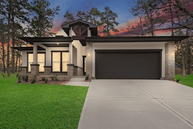 view of front of house with a garage, concrete driveway, a yard, and stucco siding