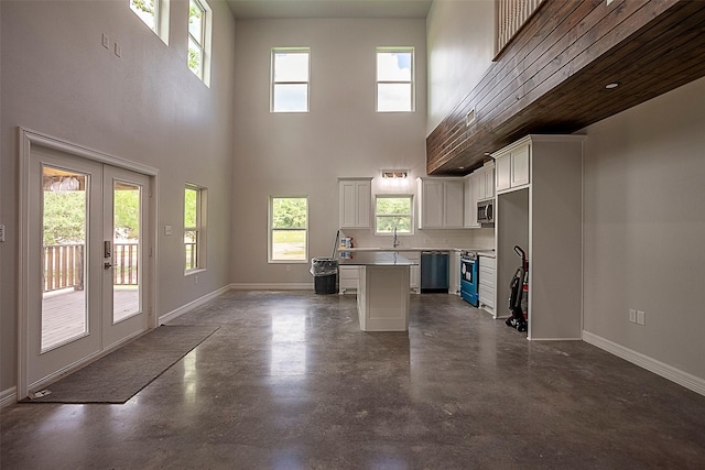 kitchen with appliances with stainless steel finishes, a center island, a sink, and baseboards