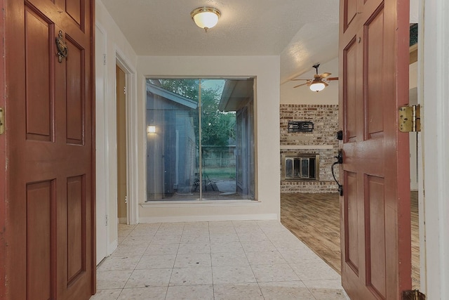 foyer entrance with a fireplace, a textured ceiling, and ceiling fan