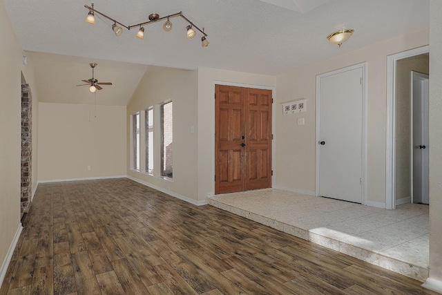 entryway featuring baseboards, lofted ceiling, ceiling fan, wood finished floors, and a textured ceiling