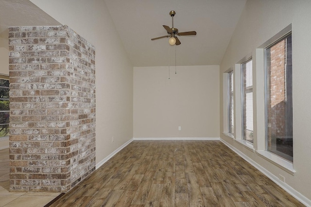 empty room with ceiling fan, baseboards, vaulted ceiling, and wood finished floors