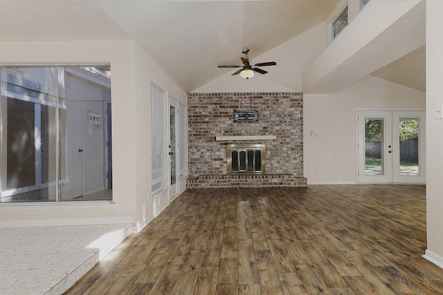 unfurnished living room featuring vaulted ceiling, french doors, a brick fireplace, and wood finished floors