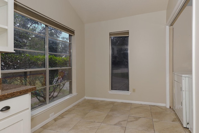 empty room featuring baseboards, vaulted ceiling, and light tile patterned flooring