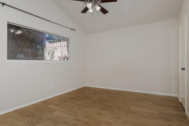 spare room with vaulted ceiling, wood finished floors, a ceiling fan, and baseboards