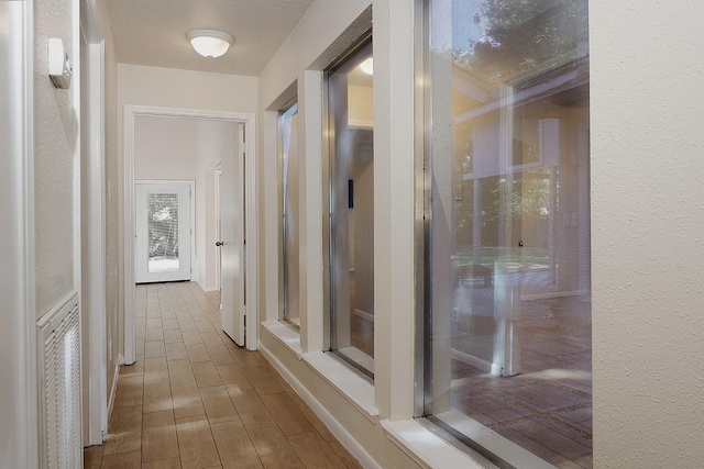 corridor featuring a textured wall and wood finish floors