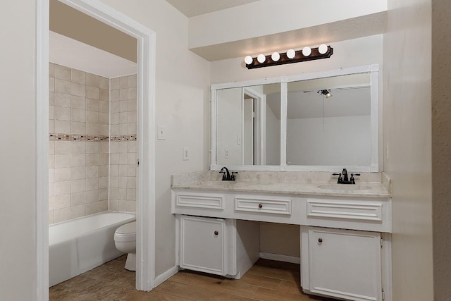 full bathroom featuring double vanity, wood finished floors, a sink, and toilet