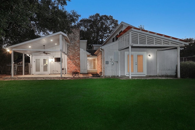 rear view of property with an outbuilding, french doors, a lawn, and a chimney