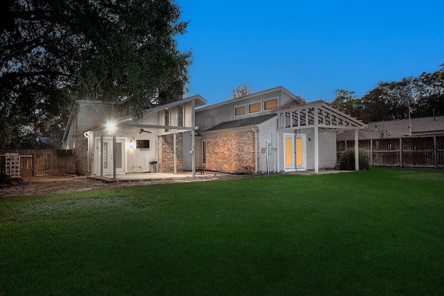 back of property with a patio area, french doors, a fenced backyard, and a yard