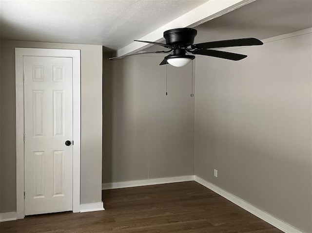 unfurnished room featuring a ceiling fan, a textured ceiling, baseboards, and dark wood-type flooring