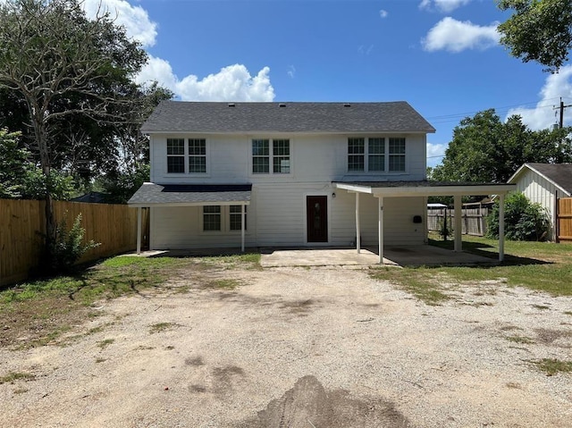 back of property with dirt driveway, a patio, an attached carport, and a fenced backyard