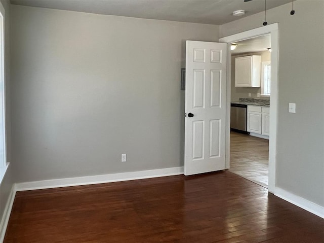 unfurnished room with dark wood-type flooring and baseboards