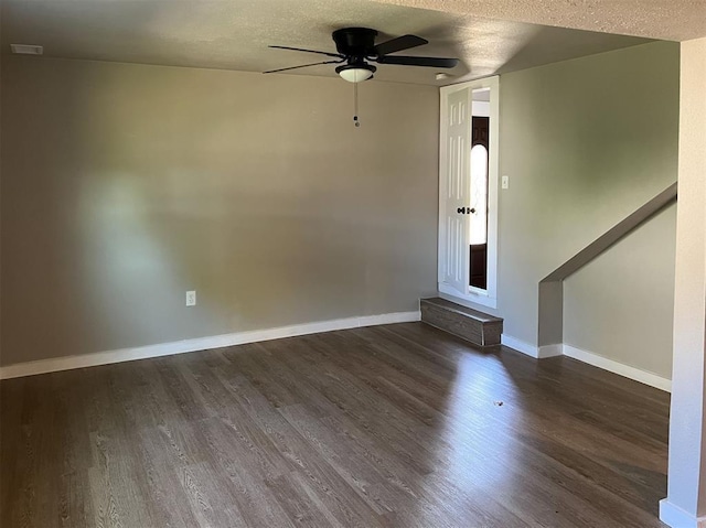 empty room with a ceiling fan, dark wood-style flooring, a textured ceiling, and baseboards