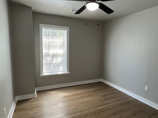 spare room with a ceiling fan, baseboards, visible vents, and dark wood-type flooring