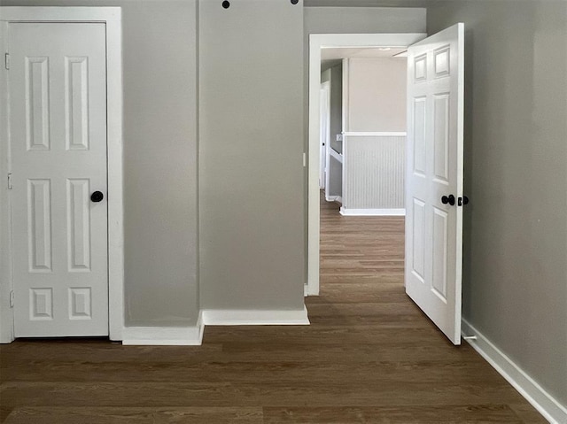 corridor featuring dark wood finished floors and baseboards