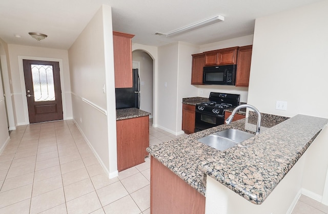 26810 Blacktail Ct, Hockley, TX 77447 - kitchen with black appliances, a sink, dark stone countertops, arched walkways, and light tile patterned floors