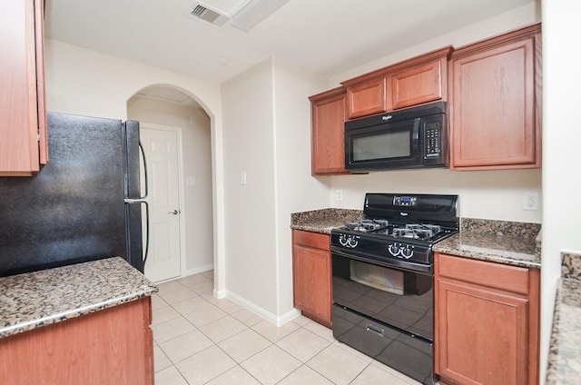 26810 Blacktail Ct, Hockley, TX 77447 - kitchen with visible vents, light stone counters, light tile patterned floors, arched walkways, and black appliances