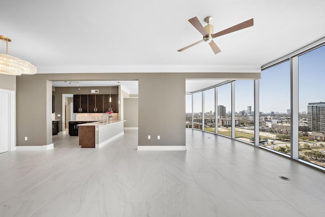 unfurnished living room with baseboards, a view of city, floor to ceiling windows, and ceiling fan