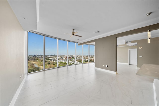 spare room featuring baseboards, visible vents, ceiling fan, expansive windows, and a city view