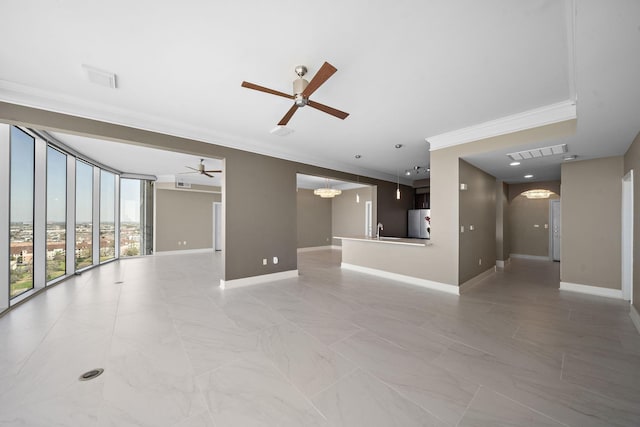 unfurnished living room with baseboards, visible vents, crown molding, a sink, and ceiling fan with notable chandelier