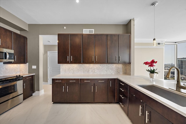 kitchen with dark brown cabinetry, visible vents, appliances with stainless steel finishes, light countertops, and a sink