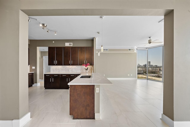 kitchen with visible vents, decorative backsplash, open floor plan, light countertops, and a sink