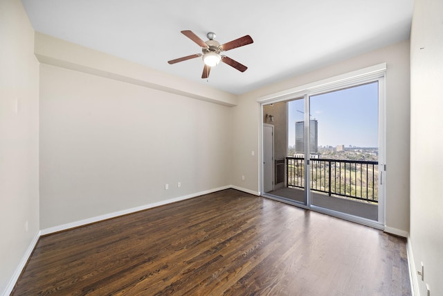 unfurnished room featuring a view of city, ceiling fan, baseboards, and wood finished floors