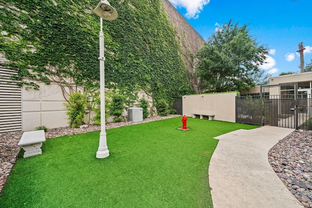 view of yard featuring a gate, fence, and central AC