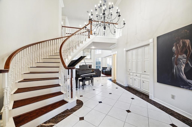 entrance foyer featuring light tile patterned floors, baseboards, a towering ceiling, stairs, and a chandelier