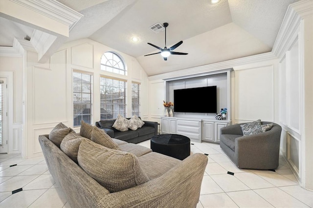 living area featuring light tile patterned floors, lofted ceiling, a decorative wall, a ceiling fan, and ornamental molding