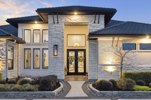 doorway to property with stone siding, a tiled roof, and stucco siding