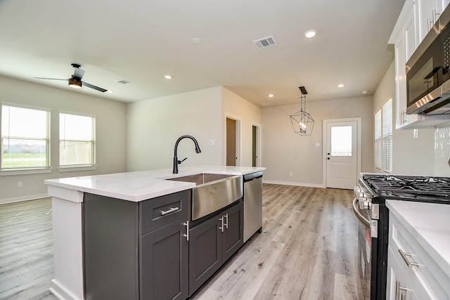 kitchen featuring stainless steel appliances, light wood-type flooring, visible vents, and a sink