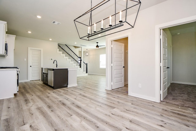 kitchen featuring a kitchen island with sink, white cabinets, visible vents, and light wood-style floors