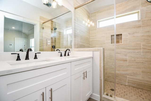 full bath with double vanity, an inviting chandelier, a sink, and a shower stall