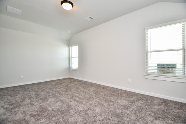 carpeted empty room featuring lofted ceiling, visible vents, and baseboards