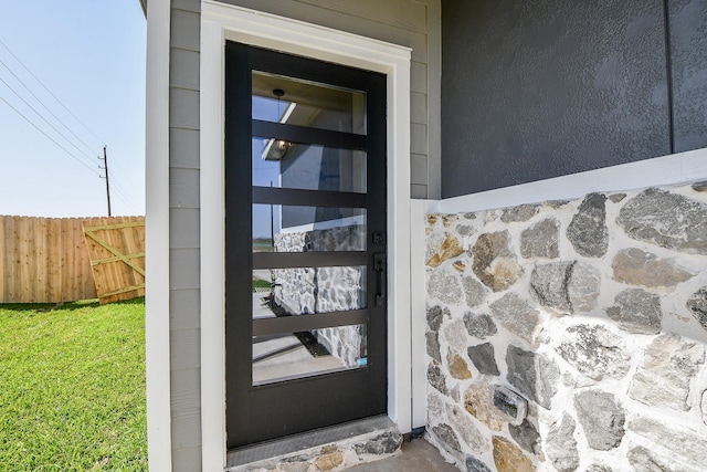 property entrance featuring stone siding and fence