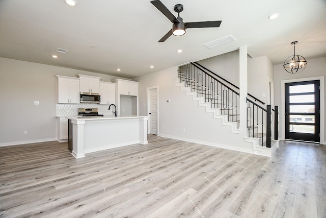 kitchen with visible vents, decorative backsplash, open floor plan, stainless steel appliances, and light wood-type flooring