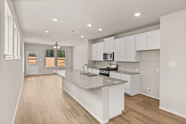 19126 Hazel Firs Ln, Magnolia, TX 77355 - kitchen featuring stainless steel appliances, a sink, decorative backsplash, baseboards, and white cabinets