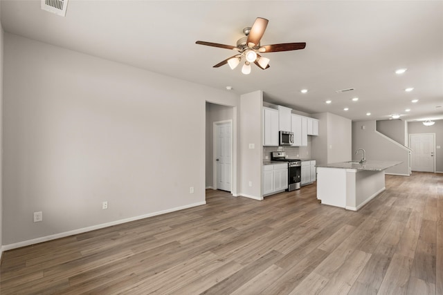 19126 Hazel Firs Ln, Magnolia, TX 77355 - kitchen with stainless steel appliances, light wood-type flooring, a ceiling fan, white cabinetry, and a sink