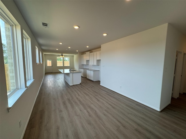 19126 Hazel Firs Ln, Magnolia, TX 77355 - kitchen with white cabinets, dark wood-style floors, baseboards, a center island with sink, and recessed lighting