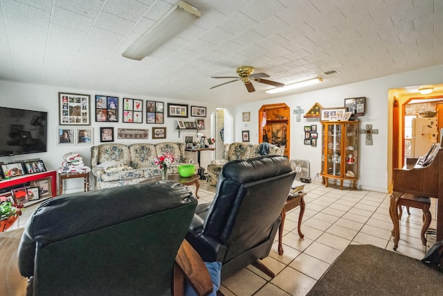 living room featuring ceiling fan, visible vents, arched walkways, and light tile patterned flooring