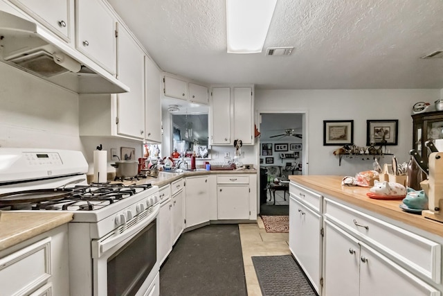 kitchen with light countertops, white cabinets, white gas stove, and under cabinet range hood